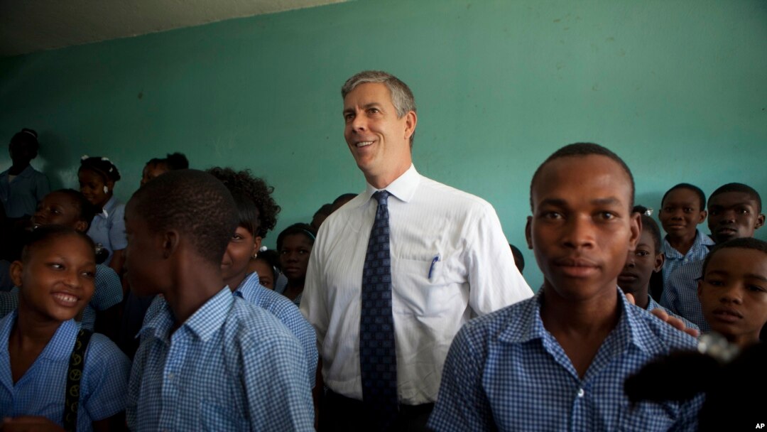U.S. Secretary of Education Arne Duncan stands with students during his visit to Lycee de Petion-Ville high school in Petion-Ville, Haiti, Nov. 5, 2013. 