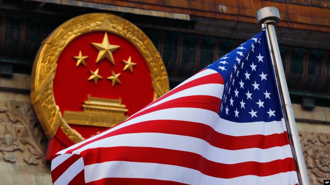FILE - An American flag is flown next to the Chinese national emblem during a welcome ceremony at the Great Hall of the People in Beijing, Nov. 9, 2017. 