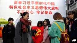 一群大學生手舉中共黨旗在寫有“習近平語錄”的宣傳板前合影。 （2017年11月19日）
