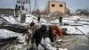  Civilians cross a river via a blown up bridge on Kyiv's northern front on March 1, 2022. (Aris Messinis/AFP)