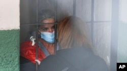 Tras las rejas, la expresidenta interina de Bolivia, Jeanine Áñez, habla con una mujer no identificada en la cárcel de una comisaría en La Paz, el 13 de marzo de 2021. 