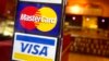 FILE - This April 22, 2005, photo, shows logos for Mastercard and Visa credit cards at the entrance of a New York coffee shop.