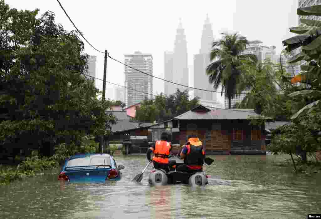 Malaysia Civil Defense Force members ride a boat to rescue the residents at a flooded area, following heavy rain fall in Kuala Lumpur.