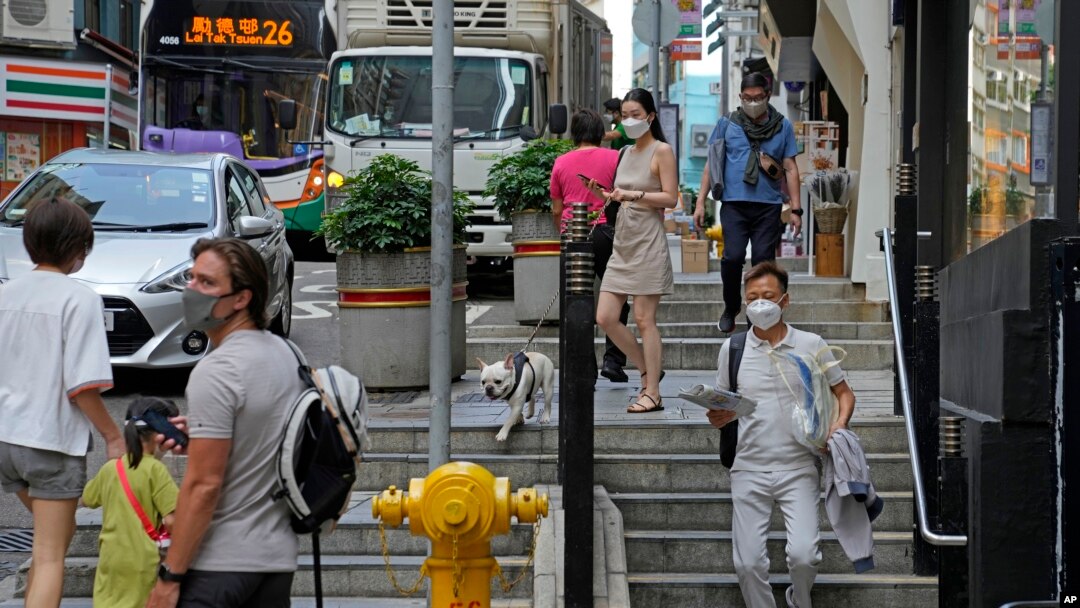 People wearing face masks walk alone a street in Hong Kong, March 15, 2022. Hong Kong on Monday reported 26,908 new coronavirus cases and 249 related deaths in its latest 24-hour period.