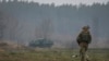 Un miembro del servicio ucraniano revisa un área cerca de los vehículos blindados de transporte de personal rusos destruidos en la línea del frente cerca de Kiev, la capital, mientras continúa la invasión de Ucrania por parte de Rusia, el 30 de marzo de 2022.