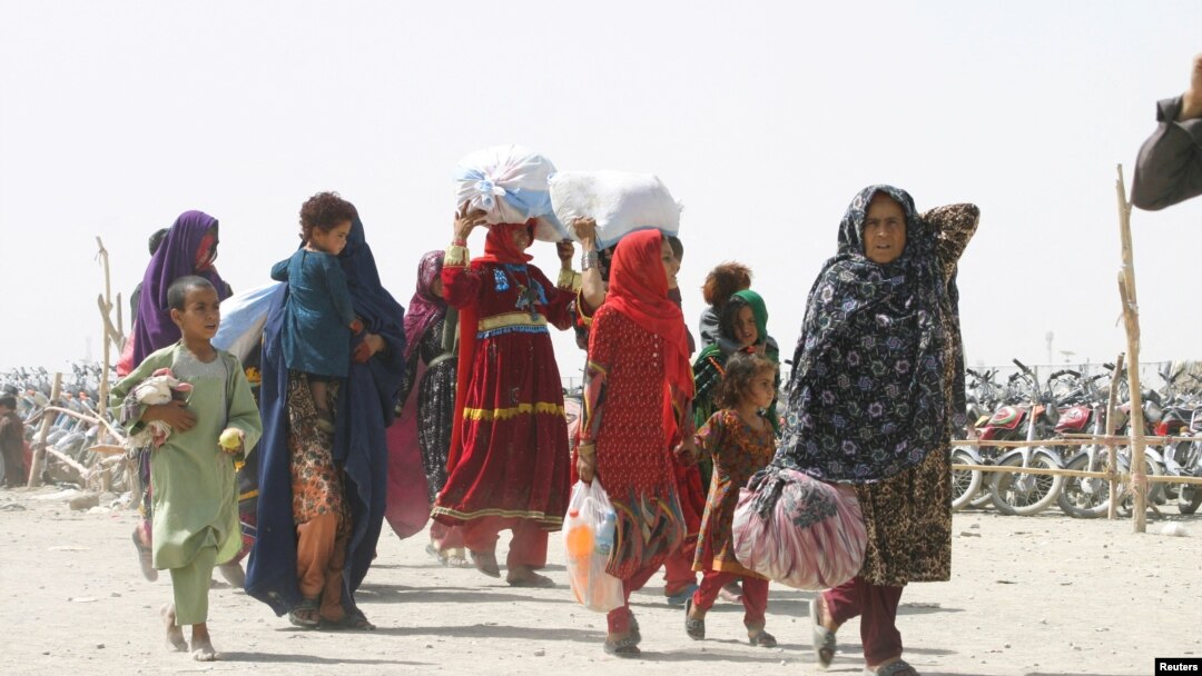 FILE - People from Afghanistan walk with their belongings as they cross into Pakistan at the 'Friendship Gate' crossing point, in the Pakistan-Afghanistan border town of Chaman, Pakistan, Sept. 7, 2021. 