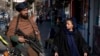 A Taliban fighter stands guard as a woman walks past in Kabul, Afghanistan, on Dec. 26, 2022. 