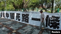 資料照：一名男子走過台北街頭懸掛的寫有「投資中國死路一條」字樣的標語。（2012年8月8日）