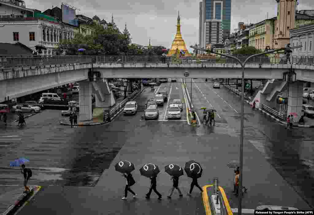 Protesters walk through a road in Yangon, Myanmar, with umbrellas bearing the number 8 in Burmese during a rally to mark the anniversary of the August 8, 1988 democracy uprising.