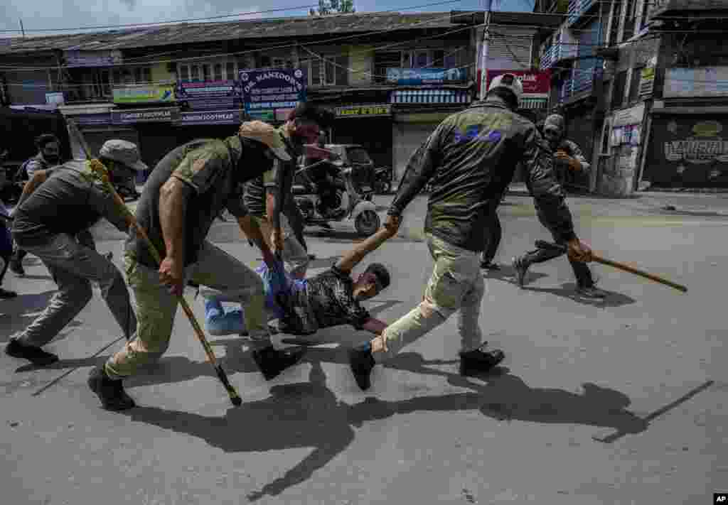 Indian policemen detain a Kashmiri Shi'ite Muslim for participating in a religious procession during restrictions in Srinagar, Indian-controlled Kashmir, .