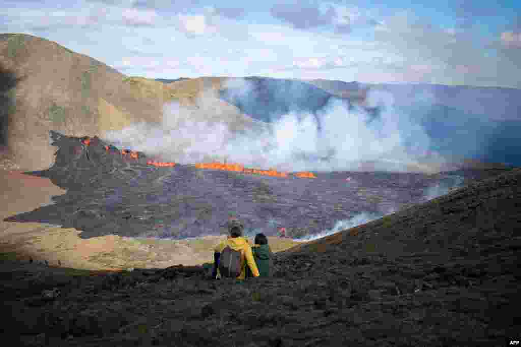 People look at the lava flowing at the scene of the newly erupted volcano at Grindavik, Iceland, Aug. 3, 2022.
