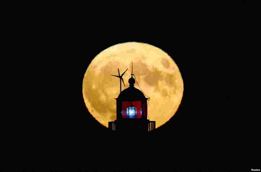 Full moon known as "Buck Moon" is seen behind a lighthouse in Saint-Nazaire, France, July 13, 2022.