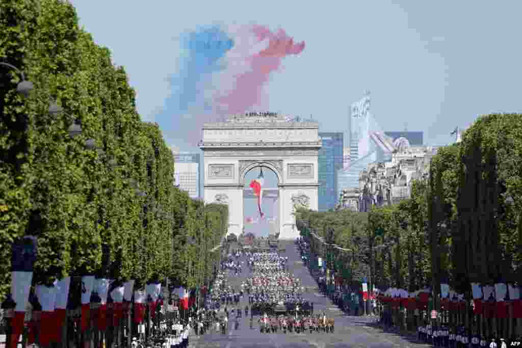 French elite acrobatic flying team "Patrouille de France" (PAF) releases smoke in the colors of the French flag as they perform a fly-over during the Bastille Day military parade on the Champs-Elysees avenue in Paris.
