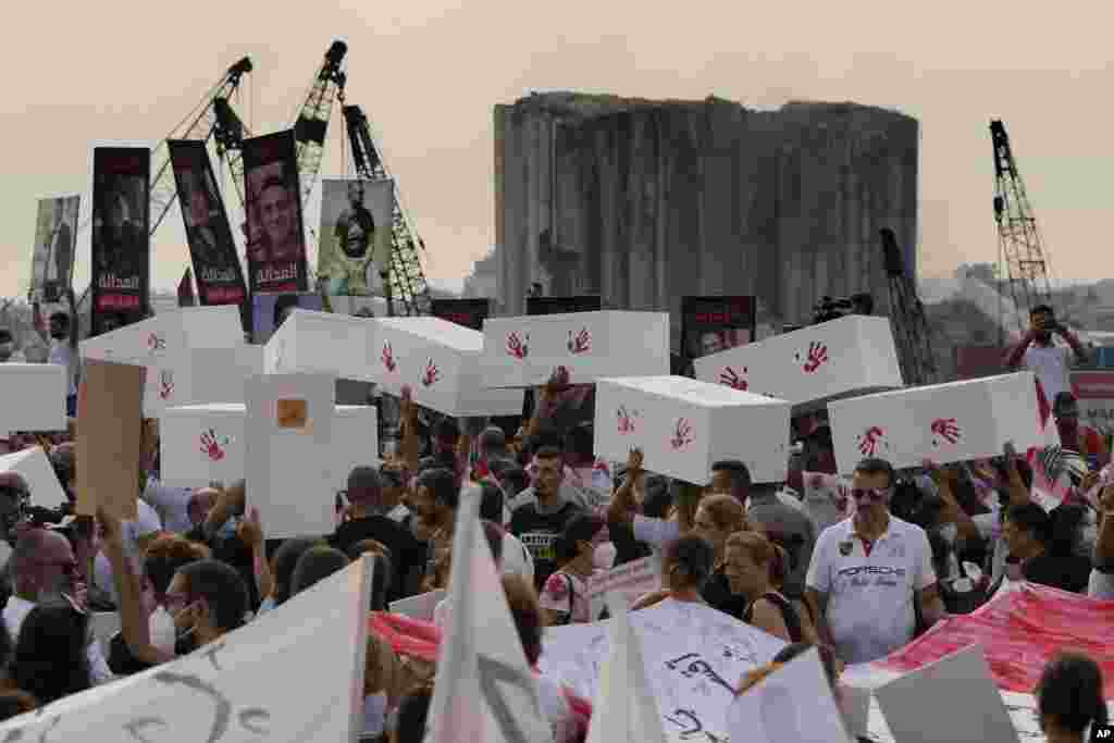 Relatives of victims of the deadly 2020 Beirut port explosion hold portraits of loved ones and symbolic coffins to mark the second anniversary of the blast, outside the port of Beirut, Lebanon.