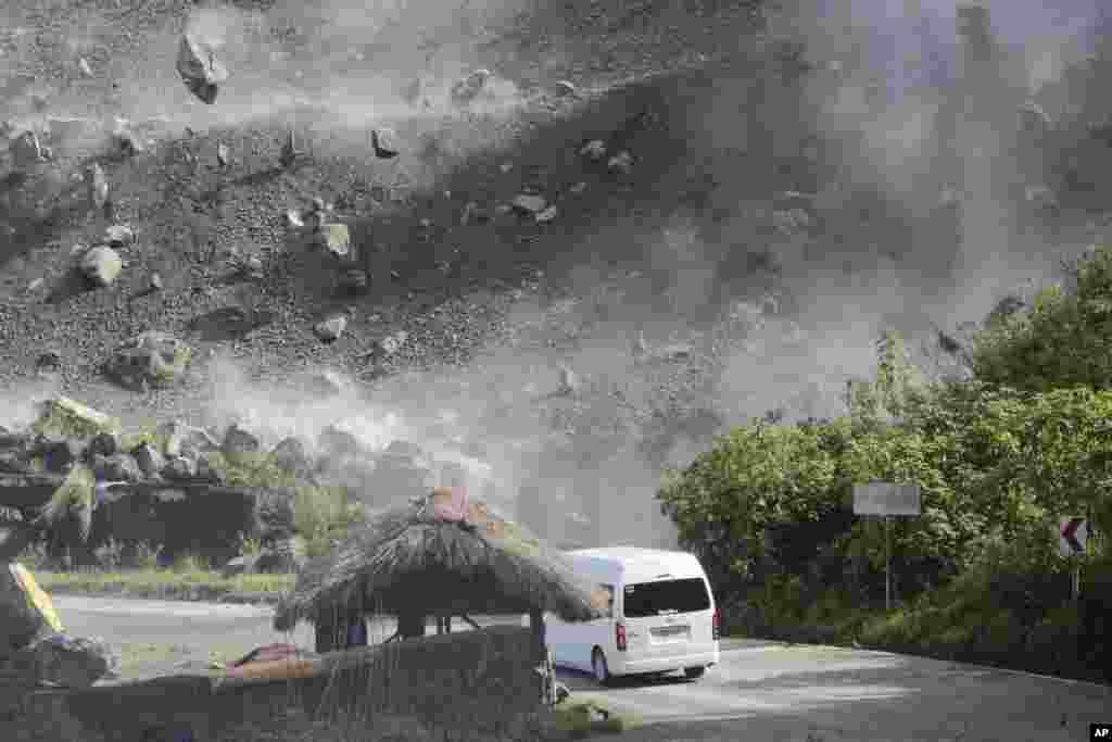 Boulders fall as a vehicle negotiates a road during an earthquake in Bauko, Mountain Province, Philippines, July 27, 2022.