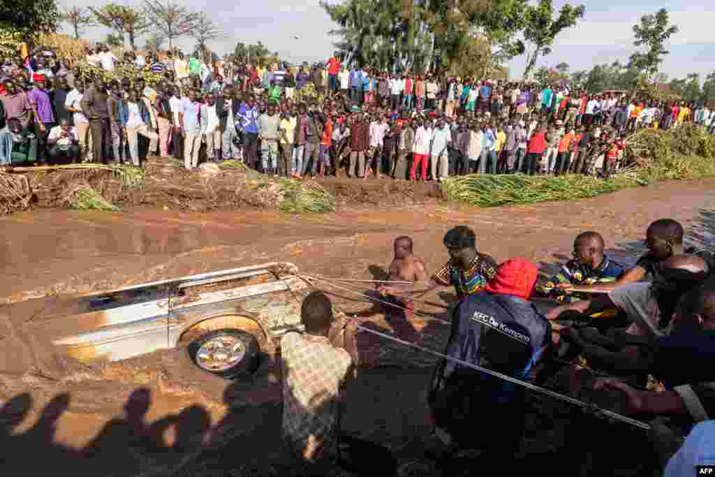 Villagers try to pull up the minibus in which 14 bodies were retrieved from inside in the River Nabuyonga in Namakwekwe, eastern Uganda, August 1, 2022. Two rivers burst their banks on the weekend after the city was battered by heavy rainfall.