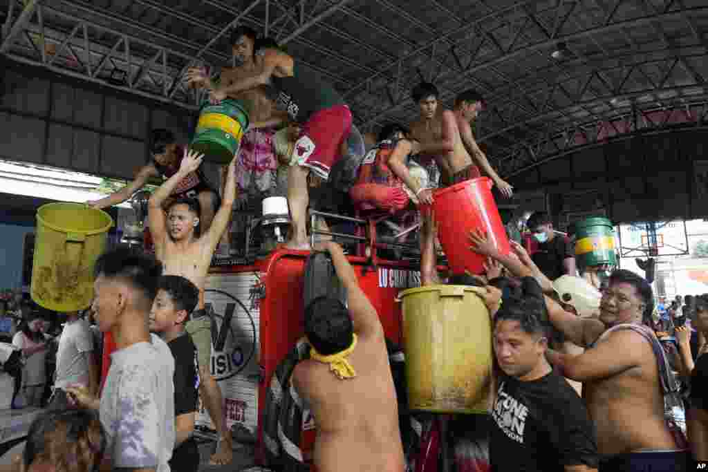 Residents refill plastic containers with water from a firetruck during a fire in Manila, Philippines.