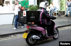 FILE - An Uber Eats food delivery courier rides her scooter in London, Sept. 7, 2016.