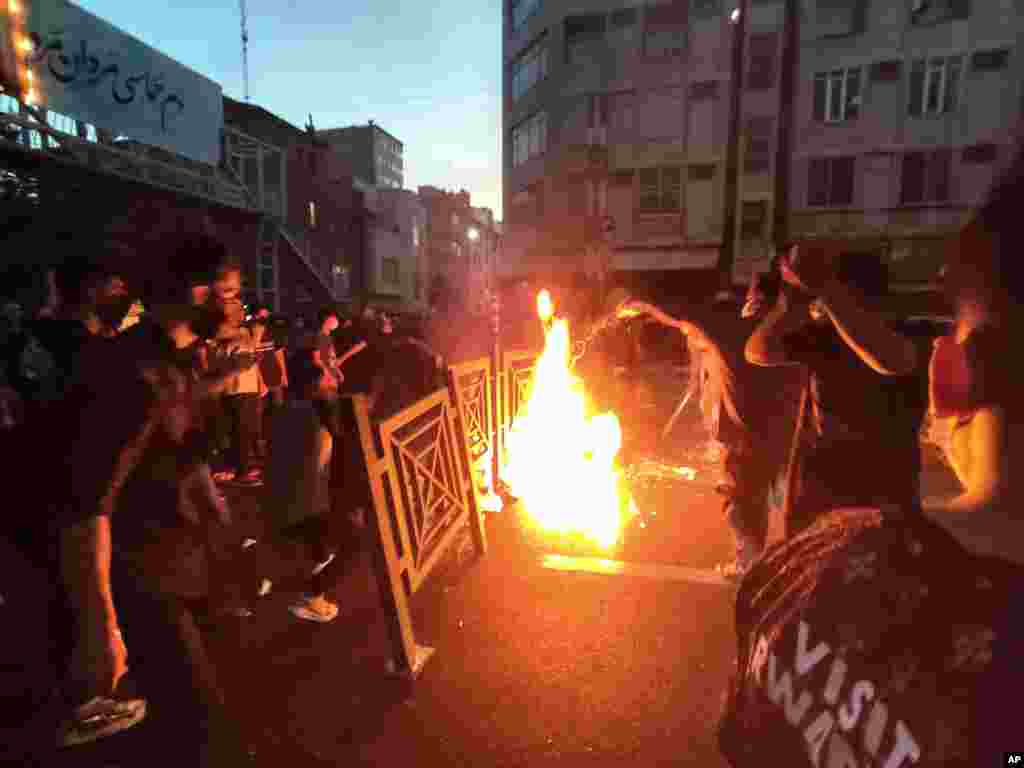 In this Sept. 21, 2022 photo, taken by an individual not employed by the Associated Press and obtained by AP outside Iran, protesters set a fire and block a street during a protest over the death of a woman who was detained over "unsuitable attire," in downtown Tehran.