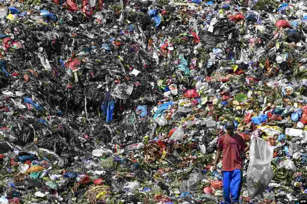 A scavenger goes through a pile of waste at a dump site in Banda Aceh, Indonesia.