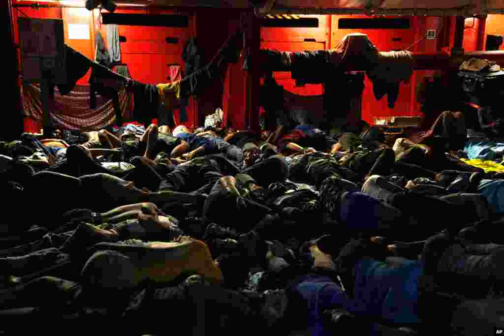Migrants sleep on the deck of the Spanish NGO Open Arms lifeguard ship after they were rescued from open waters during an operation in the international waters zone, on the Mediterranean sea.