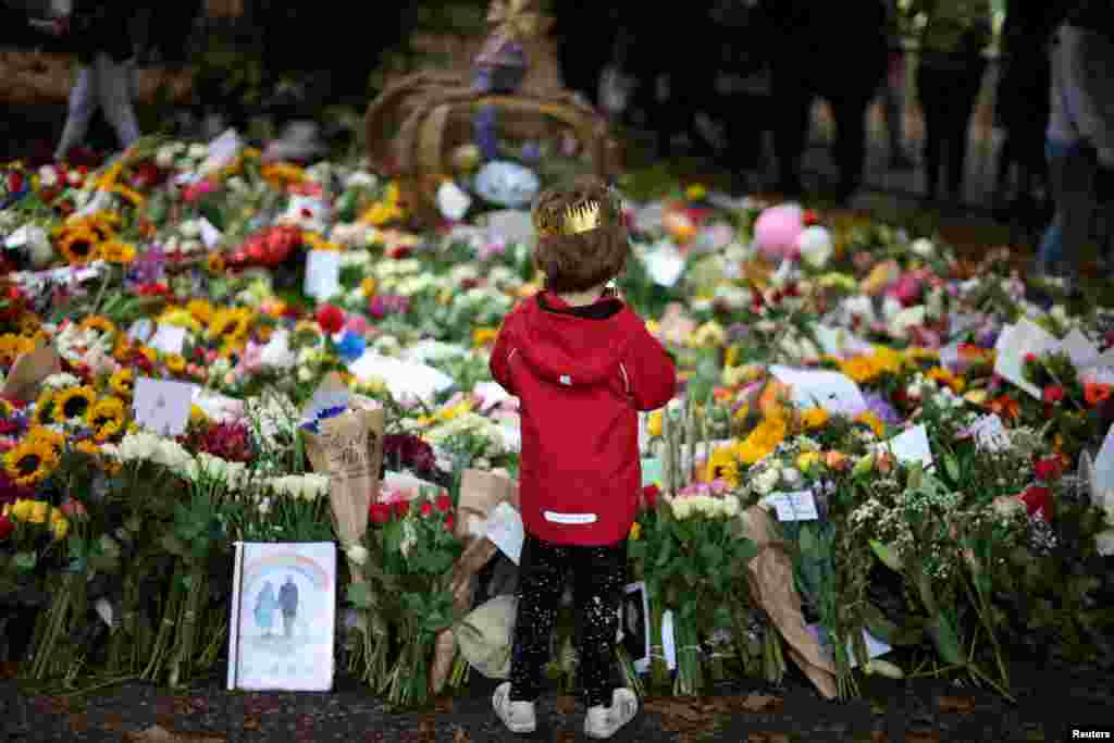 A child wearing a cardboard crown looks at floral tributes in Green Park, following the death of Britain's Queen Elizabeth, near Buckingham Palace in London.