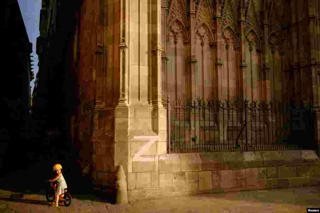 A child rides a bike next to the cathedral wall in Barcelona, painted with the letter 'Z', the symbol of the Russian military, in Barcelona, Spain, Sept. 17, 2022.