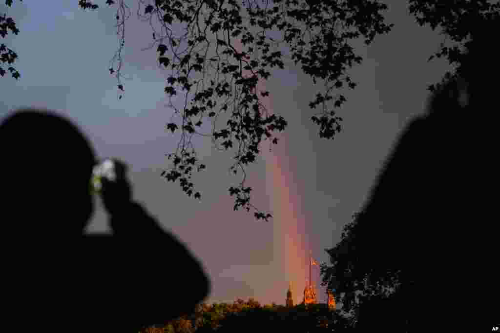 People take pictures of a rainbow over the Houses of Parliament on the eve of the funeral of Queen Elizabeth II in London, Sept. 18, 2022.