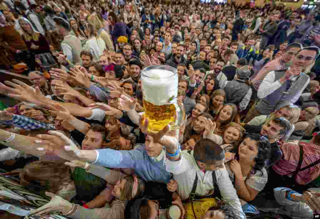 Young people reach out for free beer in one of the beer tents on the opening day of the 187th Oktoberfest beer festival in Munich, Germany, Sept. 17, 2022.