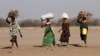 FILE - Women carry firewood on their heads outside the Kakuma refugee camp in Turkana county, northwest of Nairobi, Kenya, Feb. 1, 2018. 