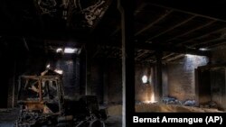 A tractor charred by a Russian attack lies inside a warehouse at a grain farm in Cherkaska Lozova, on the outskirts of Kharkiv, on May 28, 2022. (Bernat Armangue/AP)