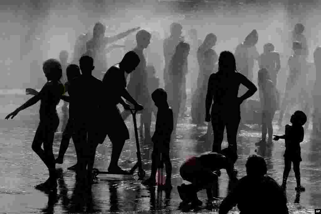 Children and adults cool off in a fountain in a park by the river in Madrid, Spain, June 12, 2022. Spain's weather service says a mass of hot air from north Africa is triggering the country's first major heatwave of the year with temperatures expected to rise to 43° C (109° F) in certain areas. 