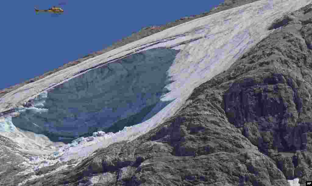A rescue helicopter hovers over the Punta Rocca glacier near Canazei, in the Italian Alps in northern Italy, a day after a huge chunk of the glacier broke loose, sending an avalanche of ice, snow, and rocks onto hikers.
