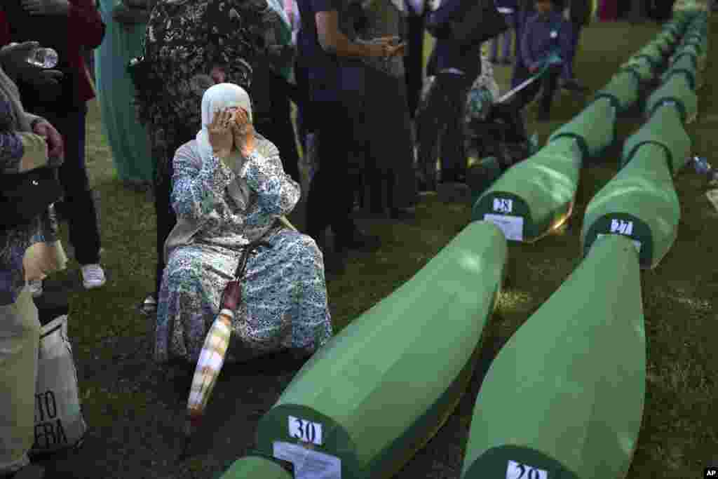 A Bosnian Muslim woman Bahta Aljic mourns next to the coffin containing remains of her husband who is among 50 newly identified victims of Srebrenica Genocide in Potocari, Bosnia-Herzegovina.