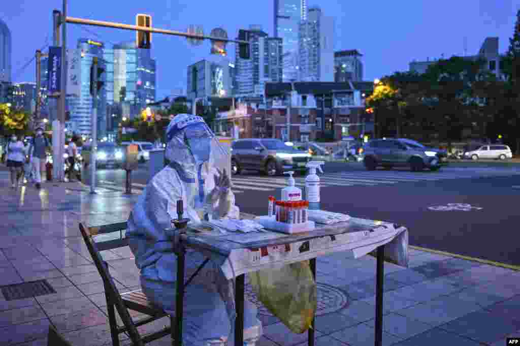 A health worker waits to test people for COVID-19 on a street next to a residential area in the Jing'an district of Shanghai.