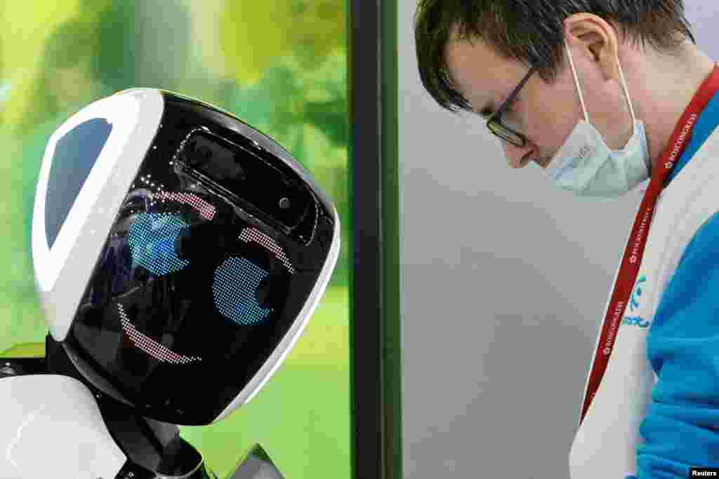 A participant stands next to a robot during the St. Petersburg International Economic Forum (SPIEF) in Saint Petersburg, Russia.
