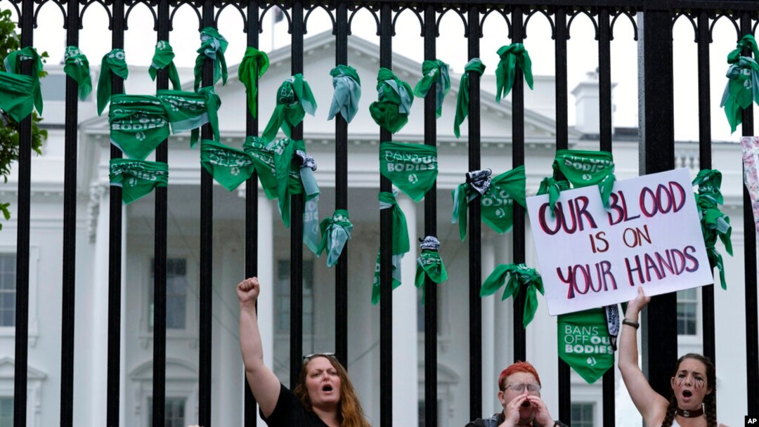 Abortion-rights demonstrators shout slogans after tying green flags to a fence at the White House during a protest to pressure the Biden administration to act and protect abortion rights, in Washington, July 9, 2022.
