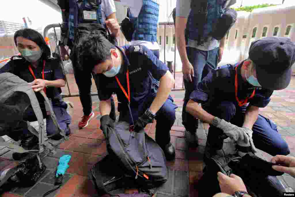 Police officers inspect journalists' bags at a media position outside the Hong Kong West Kowloon railway station, before the 25th anniversary of the former British colony's handover to Chinese rule, in Hong Kong.