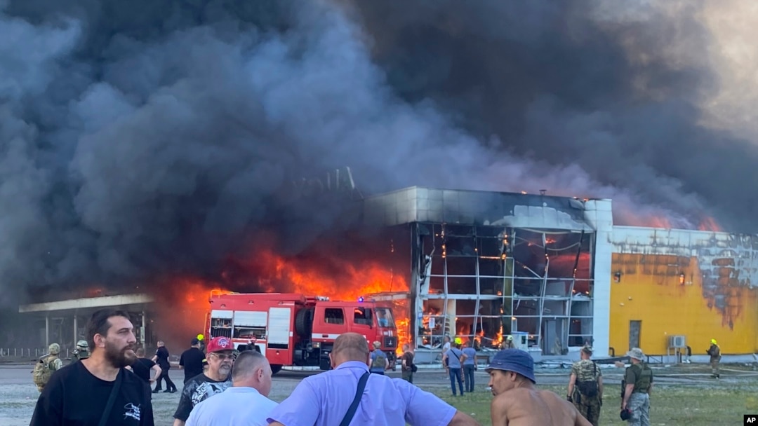 La gente observa cómo el humo brota después de que un ataque con misiles rusos golpeó un centro comercial lleno de gente, en Kremenchuk, Ucrania, el lunes 27 de junio de 2022.
