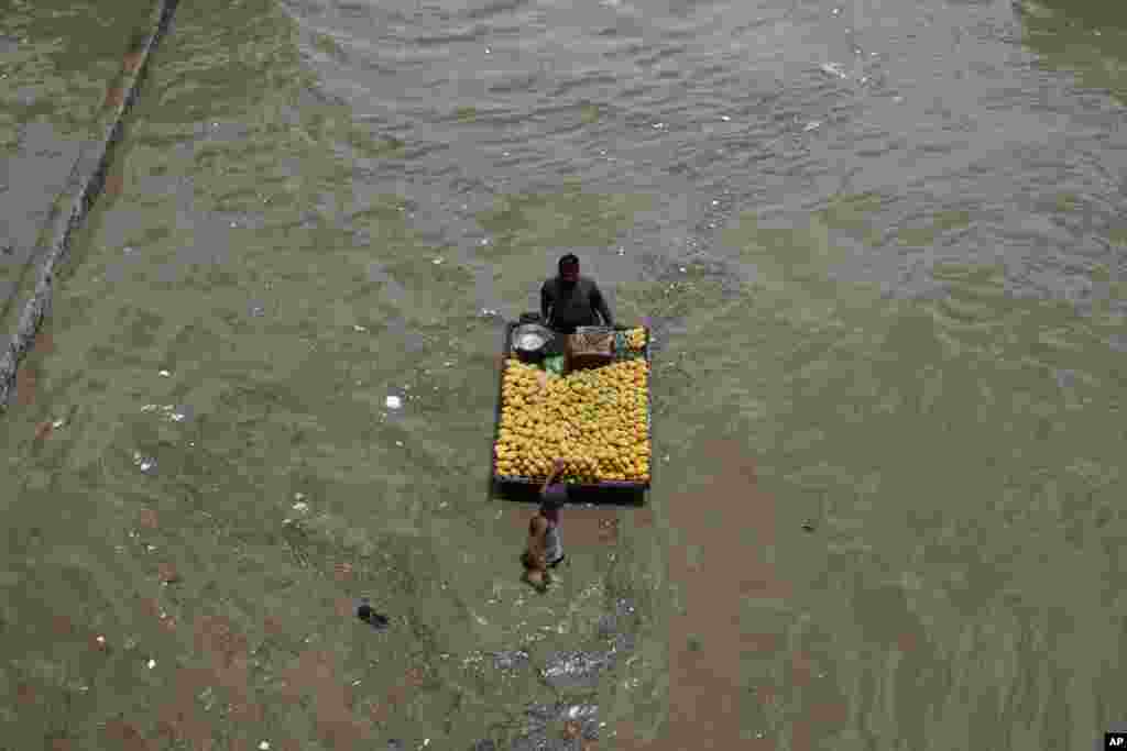 A fruit vendor navigates a flooded road after a heavy rainfall in Karachi, Pakistan.