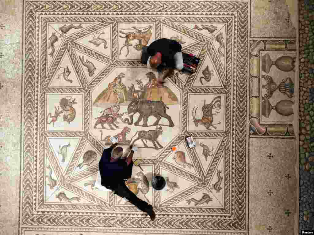 Workers clean a restored Roman-era mosaic after it was put on display at its original site in Lod, now an Israeli city where an archaeological center has been inaugurated.