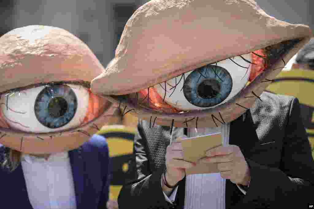 Activists wearing masks depicting large eyeballs attend a protest against planned updates of the country's national security laws, after a draft was leaked to the media earlier this month, in Bucharest, Romania.