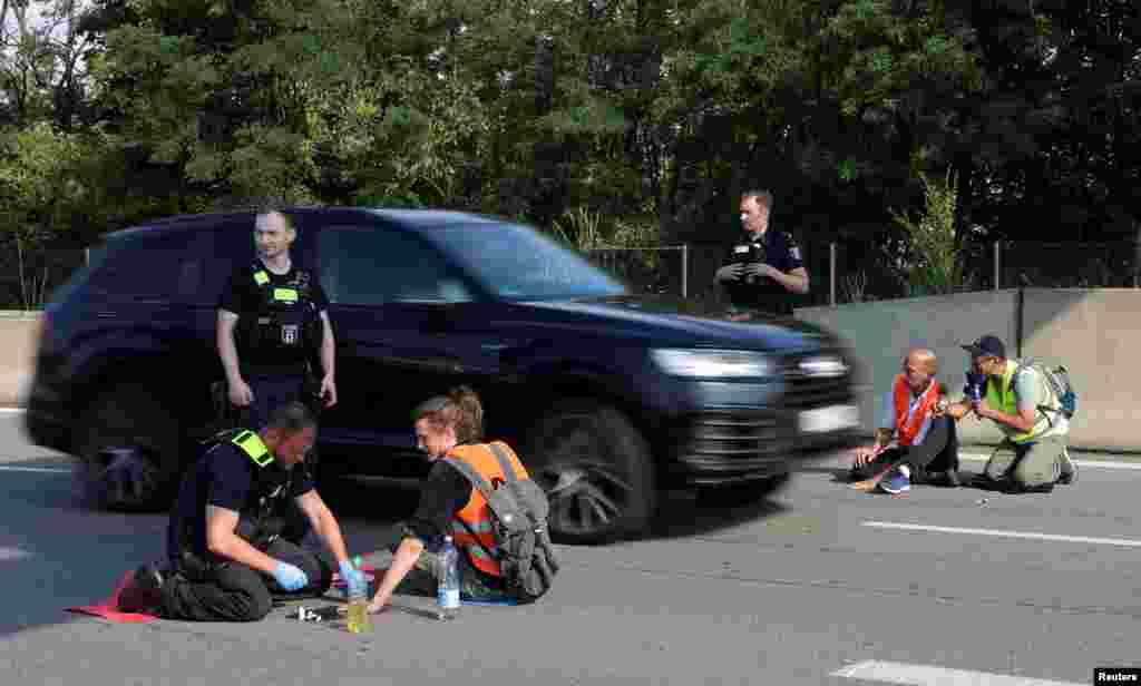 A police officer removes a "Letzte Generation" (Last Generation) activist that glued his hand to the road, as they block a highway for an end to fossil fuels and against oil drilling in the North Sea, in Berlin, Germany.