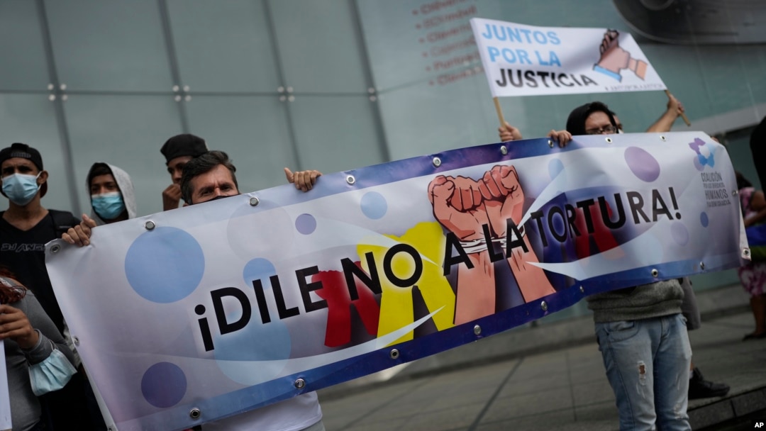 Manifestantes que denuncian violaciones de derechos humanos contra sus familiares sostienen un cartel que dice en español "¡Di no a la tortura!" frente a la sede del a oficina para el desarrollo, de la ONU, en Caracas, Venezuela, el 29 de octubre de 2021.