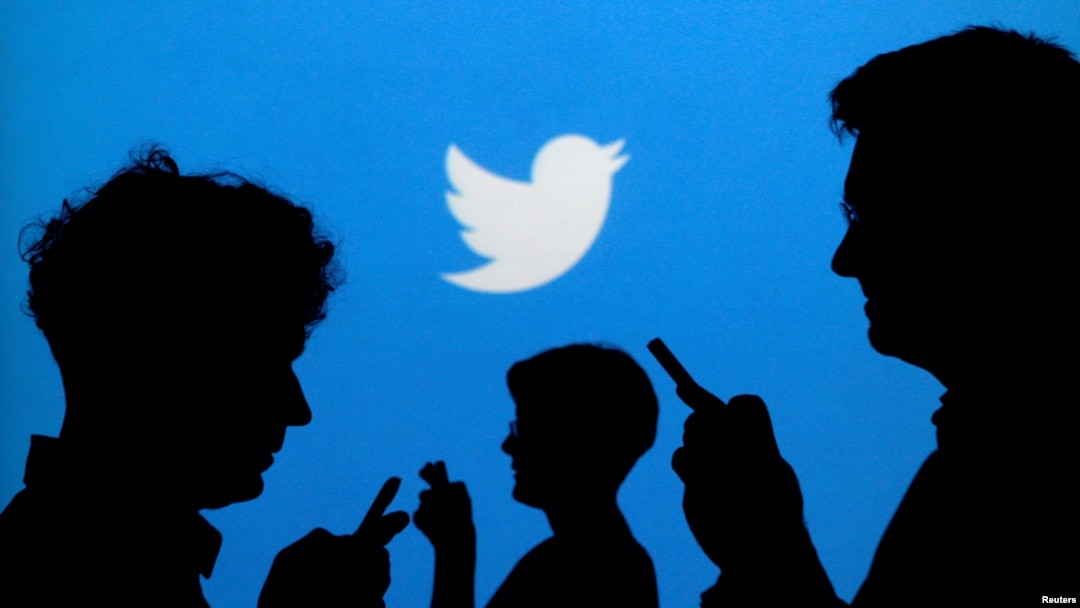 FILE - People holding mobile phones are silhouetted against a backdrop projected with the Twitter logo in this illustration made Sept. 27, 2013. 