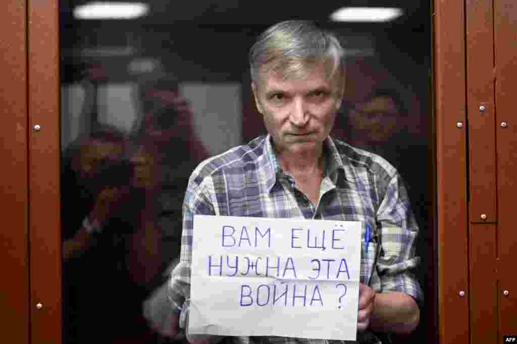 Moscow city deputy Alexei Gorinov, accused of spreading "knowingly false information" about the Russian army fighting in Ukraine, stands with a poster reading ""Do you still need this war?" inside a glass cell during the vedict hearing in his trial at a c