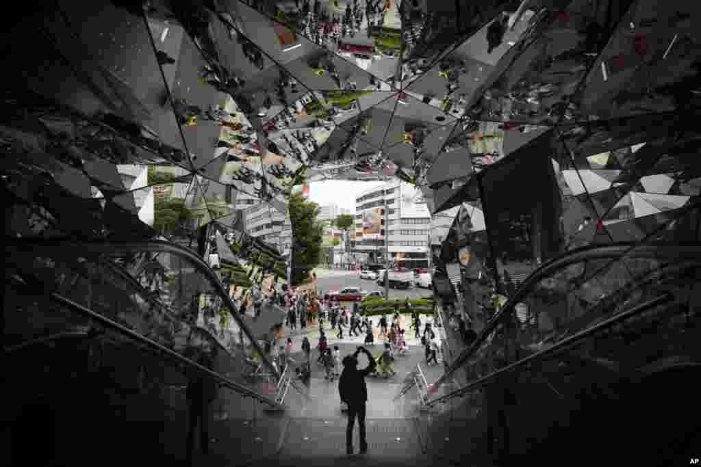 A tourist takes pictures of the entrance of a shopping mall decorated with mirrors in Harajuku district of Tokyo, Japan.