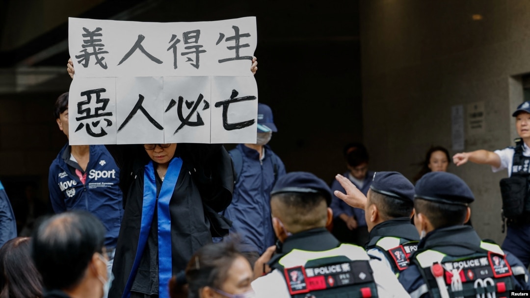Elsa, the foster mother of defendant Hendrick Lui, holds a banner reading "The righteous shall live; the wicked shall perish" outside the West Kowloon Magistrates' Courts building after the sentencing of 45 pro-democracy activists in Hong Kong, Nov. 19, 2024. 