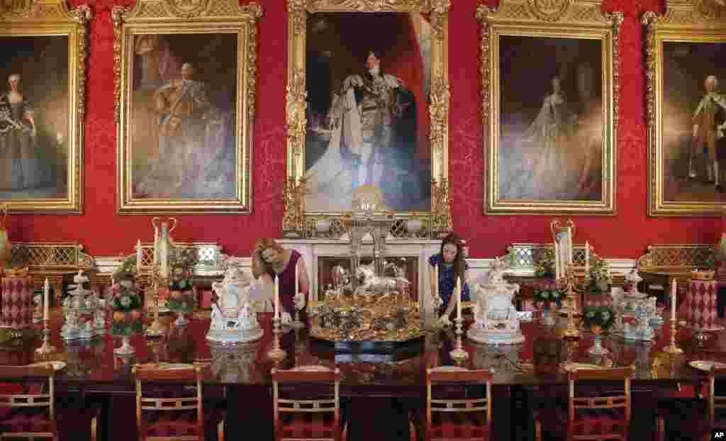 Palace staff arrange the dining table, a copy of Queen Victoria's reign dessert table, on display, as part of an exhibition at Buckingham Palace, in London.