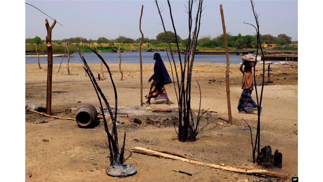 FILE - Chadian women walk past destroyed homes, in the Lake Chad shore village of N'Gouboua, March 5, 2015, following a scorched-earth attack by Boko Haram militants.